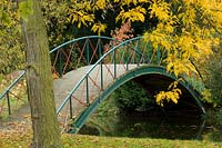 Small ornamental footbridge over river surrounded by autumnal trees. 