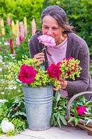Woman enjoying the scent of newly picked Paeonia - Peony. 