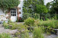 Flowerbeds and gravelled area planted with Libertia grandiflora, grasses, Paeonia and Geum. 