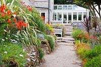 Path leading towards the house is framed with phormiums, cordylines, crocosmias, osteospermums and euphorbias.