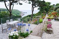 View from the terrace across the garden to Lamorna Cove and the sea beyond, framed by Scots Pines. 