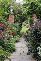 The Italian Garden. A stone path leads between beds of dahlias. On the left 'Mystic Enchantment' and 'Waltzing Mathilda'. On right Dahlia 'Magenta Star'.