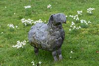 A metal sheep sculpture stands among naturalised snowdrops.
