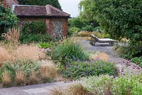 A stone terrace with loungers is reached via a straight path edged in hardy geraniums, penstemons and clumps of ornamental grasses â€” Deschampsia flexuosa 'Goldtau' and Pennisetum macrourum, African feather grass.