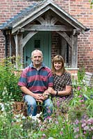 Garry and Alison Szafranski in their front garden next to a box parterre filled with cottage garden planting.
