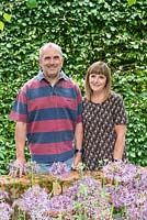 Garry and Alison Szafranski in their front garden in front of a hornbeam hedge and behind a bed of Allium cristophii.