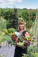 Alison Szafranski with a trug of freshly picked vegetables and edible flowers picked from her kitchen garden.