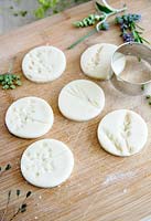 Salt dough with impressions left by pressed flowers cut into circular discs 