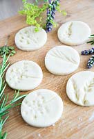 Circular salt dough discs with impressions left by flowers 