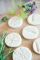 Circular discs of salt dough with impressions left by flowers to make gift tags