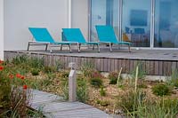 Aqua blue chairs on wooden decked terrace in seaside garden. 