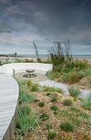 Modern, landscaped seaside garden, with curved bench and gravel borders.