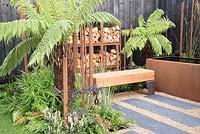 Slate and gravel path leading to oak bench, Corten water container - Bee's Gardens: The Penumbra, RHS Tatton Park Flower Show 2018