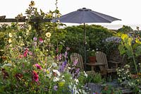 The Old Stone Cottage, Beesands, South Devon. Seating area with parasol and mixed annual planting in cottage garden.