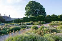 Miserden Park, Gloucestershire, summer, with spectacular views over a deer park and rolling Cotswold hills beyond. The formal parterre style garden with allium seed heads in summer.