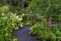 Winding black path leading to curved benches with a mixed border - The Smart Meter Garden, RHS Hampton Court Palace Flower Festival 2019