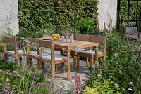 Dining area surrounded by herbaceous planting with Pinus mugo - The Viking Cruises Lagom Garden, RHS Hampton Court Palace Flower Festival 2019