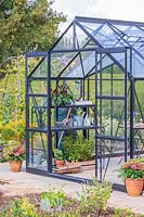 Large greenhouse with double sliding doors in vegetable garden.