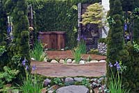 View of garden showing moss walls, timber decking and blue Iris flowers