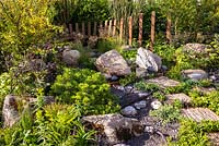 Use of natural rock and stone, with green foliage planting. RHS Hampton Court Palace Garden Festival 2019. Sponsors: Kebony, CED Stone, R and G Metal Products, William's Art  and Design, Practicality Brown.