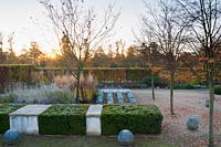 Walled garden designed by Brita von Schoenaich featuring Amelanchier x grandiflora 'Robin Hill', clipped box blocks, stone spheres and herbaceous perennials including Perovskia atriplicifolia planted in narrow lines at Marks Hall Gardens in autumn.