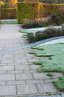 Walled garden designed by Brita von Schoenaich features hornbeam hedges and a ribbon of undulating inlaid grey blocks interspersed with planting including sedums, asters and grasses at Marks Hall in autumn.