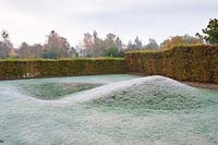 Walled garden designed by Brita von Schoenaich shaped by hornbeam hedges and mini earthworks including a representation of the turning of the earth at the start of the year, at Marks Hall Garden in autumn.
