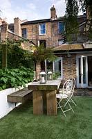 Wooden dining table and benches in urban garden. 