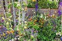 The Childrens garden with lots of colurful planting and a wildlife bug house in the Montessori Centenary Children's Garden at RHS Chelsea Flower Show 2019