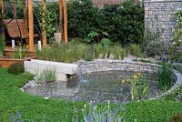 The Harmonious Garden of Life. An environmentally sustainable courtyard with a pond that is kept clean by a reed bed, encircled in clover to enrich the soil. A pergola swingseat is edged in bamboo to purify the air. Sponsors: Mr and Mrs Cawthorn, Margheriti Piante.