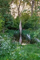 Bronze shard by David Harber set in a pool surrounded by Iris pseudacorus and wild planting of Cow Parsley- The Savills and David Harber Garden, RHS Chelsea Flower Show 2019.