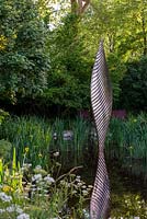 Bronze shard by David Harber set in a pool surrounded by Iris pseudacorus and wild planting of Cow Parsley - The Savills and David Harber Garden, RHS Chelsea Flower Show 2019.