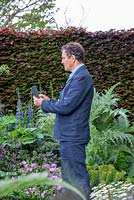Monty Don taking a picture on his smartphone whilst filming on The Morgan Stanley Garden, RHS Chelsea Flower Show 2019.