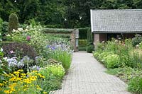 View along paved path with flowerbeds either side towards entrance. Flower beds contain: Hydrangea, Allium, Hibiscus, Rudbeckia and Echinacea