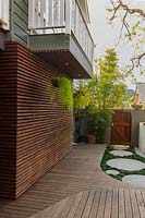 A garage wall that has been clad in hardwood timber slats in a horizontal pattern with two hanging baskets planted with succulents.