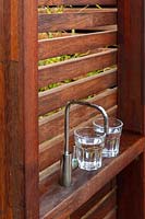 A freestanding hardwood timber screen with a in built tap fro cold drinking water and two full glasses of water.