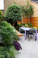 Small contemporary London garden with raised bed and bespoke garden seating with table and chairs.
