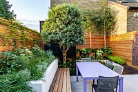 Small contemporary London garden with raised bed, bespoke garden seating with table and chairs