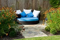 Paved relaxation area in front of a boundary fence, privacy from tall perennials such as Helenium