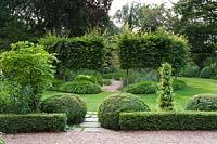 Formal garden with clipped topiary and lawn with circle of pleached Carpinus - Hornbeam - trees 