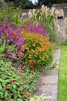 Border in the front garden including helenium, persicaria, salvia and lythrum at York Gate Garden, Adel in July.