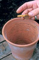 Placing a crock to cover the drainage hole of a clay pot
