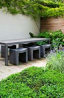 Modern, concrete table and stools on wooden decked platform. 