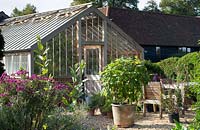 View over gravel area to traditional brick and timber framed greenhouse. 