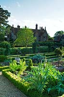 A formal garden with clipped Buxus hedges and gravel pathways - Hindringham Hall, Norfolk. 