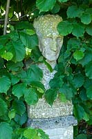 Statue of man standing among foliage