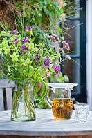 Herbal ice tea and bouquet of cut flowers in a vase, on a table