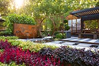 Pavilion style Chinese garden, with a freestanding water feature, moongate, stepping stones, striped paving , limestone rock garden feature, planter boxes, stone mountain range, printed glass panels, steps 