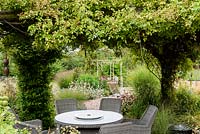 An arbour covered with rambling roses providing a shady dining area on hot days.