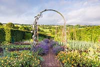 The vegetable garden with herringbone brick path edged with catmint and marigolds. Iron work by James Blunt